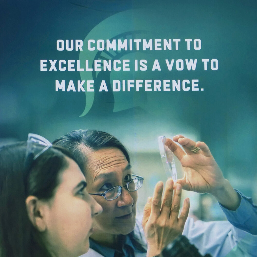 Closeup of banner showing two researchers with the headline "Our commitment to excellence is a vow to make a difference"