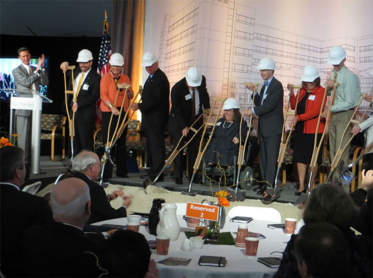 Ground breaking photo with key individuals using custom crutch-like shovels.