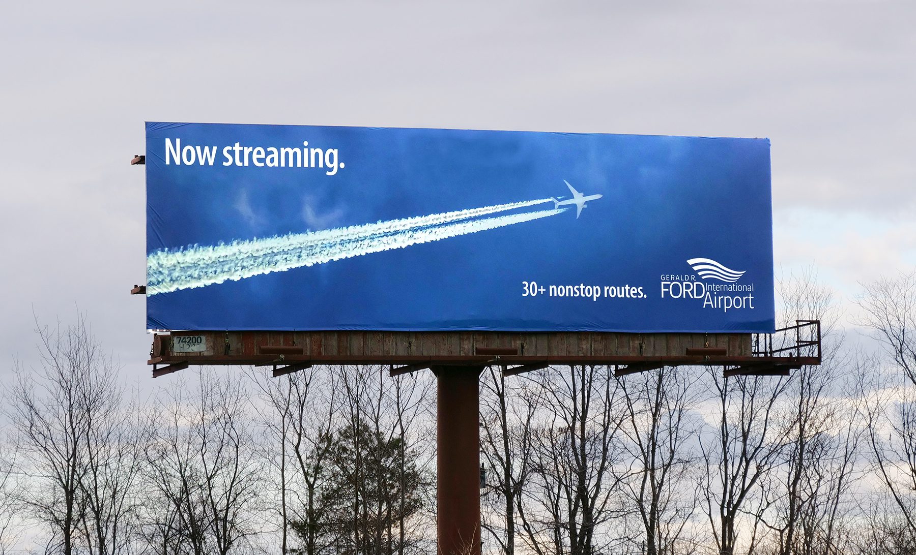 Out of home bulletin showing blue sky and jet trail with headline "Now streaming"