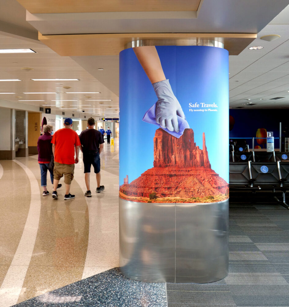 Column wrap on the concourse showing hand with latex glove cleaning a rock formation.