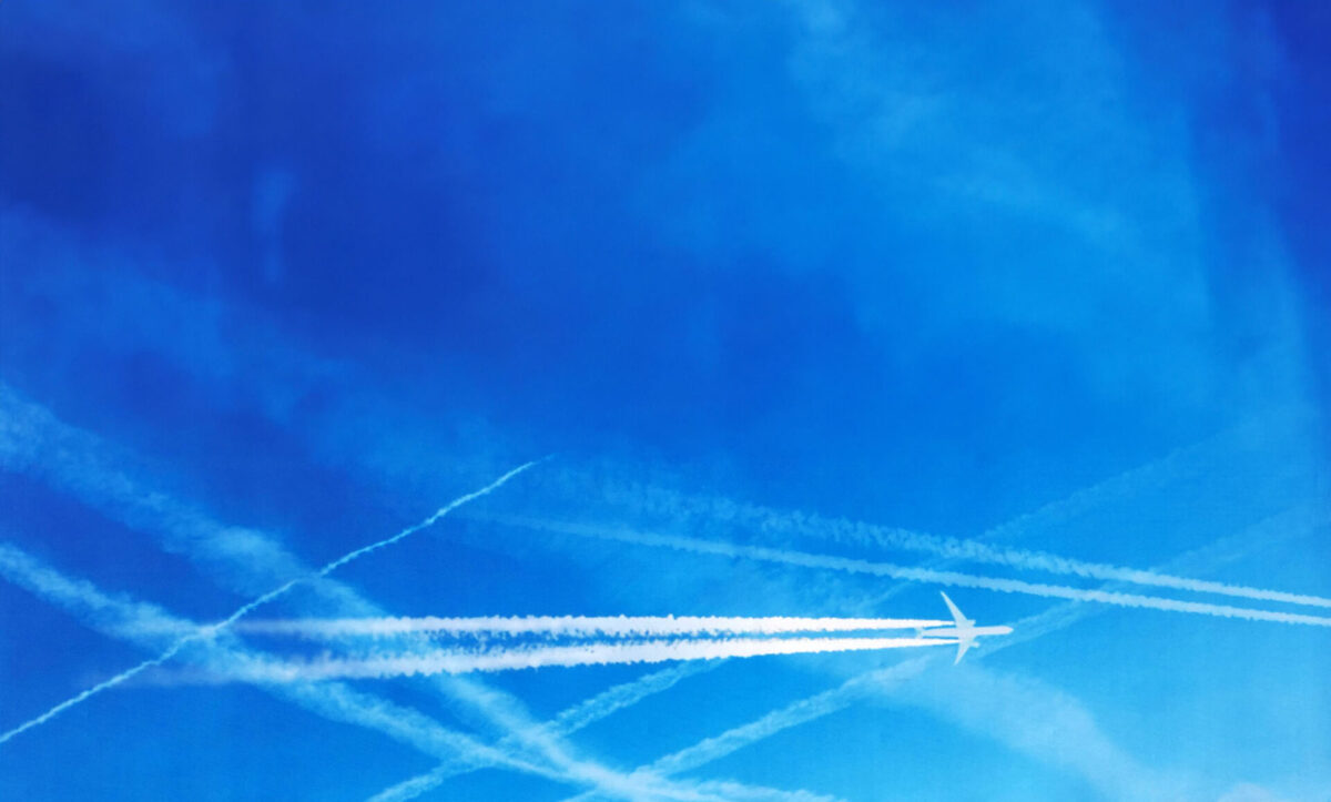 Blue sky with jet trails and plane.
