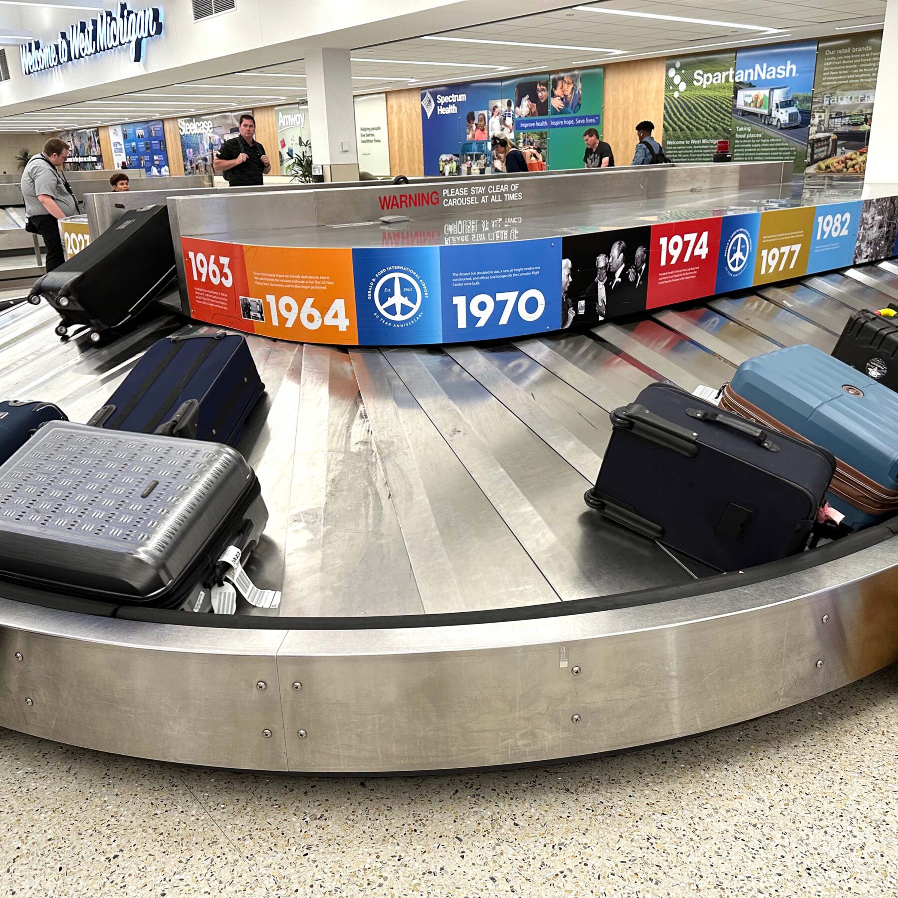 Nontraditional guerrilla installation on the Gerald R. Ford International Airport baggage claim, featuring a 60-year historical timeline.