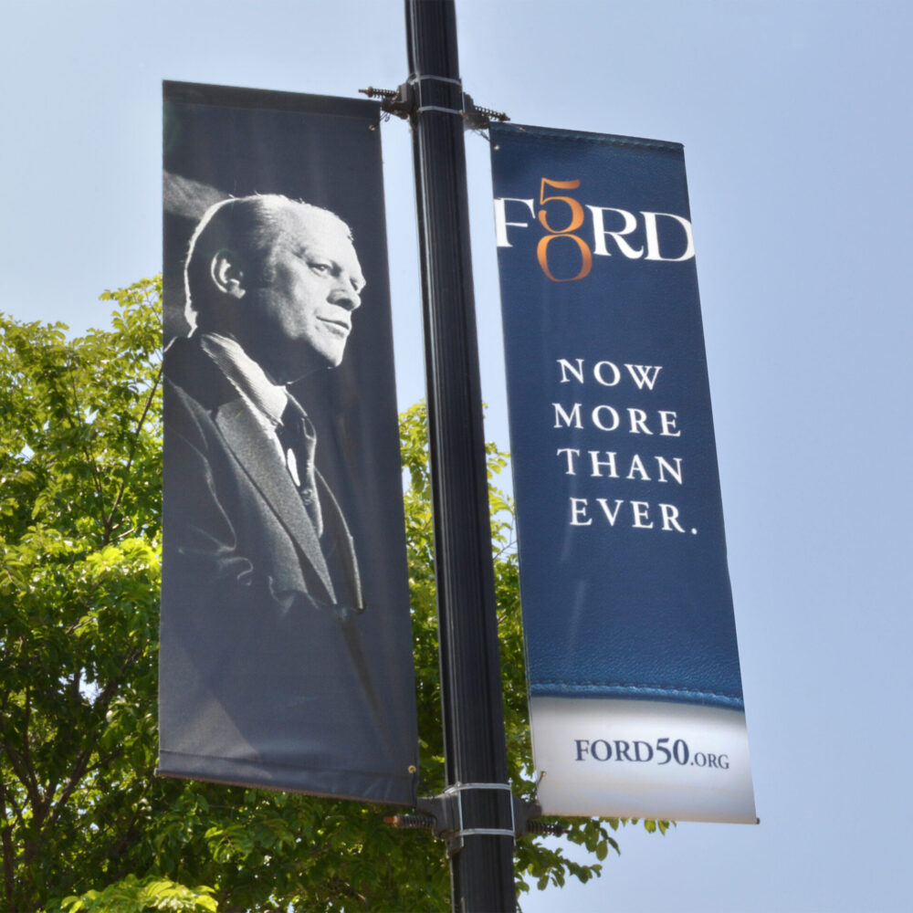Double street pole banners with headline "Now more than ever" and photo of President Ford.
