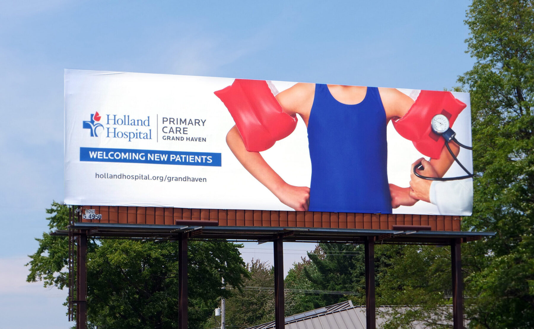 Billboard for Holland Hospital with a child wearing pool floaties. One of them looks like a blood pressure cuff. “Welcoming new patients.”