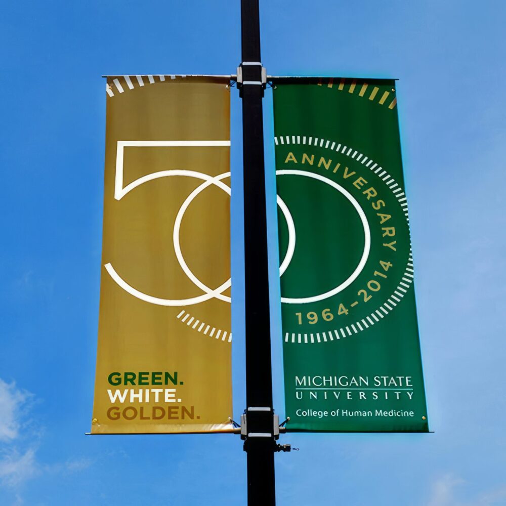 Street pole banners with the 50th anniversary logo split between the two with a gold background on the left & a green background on the right.