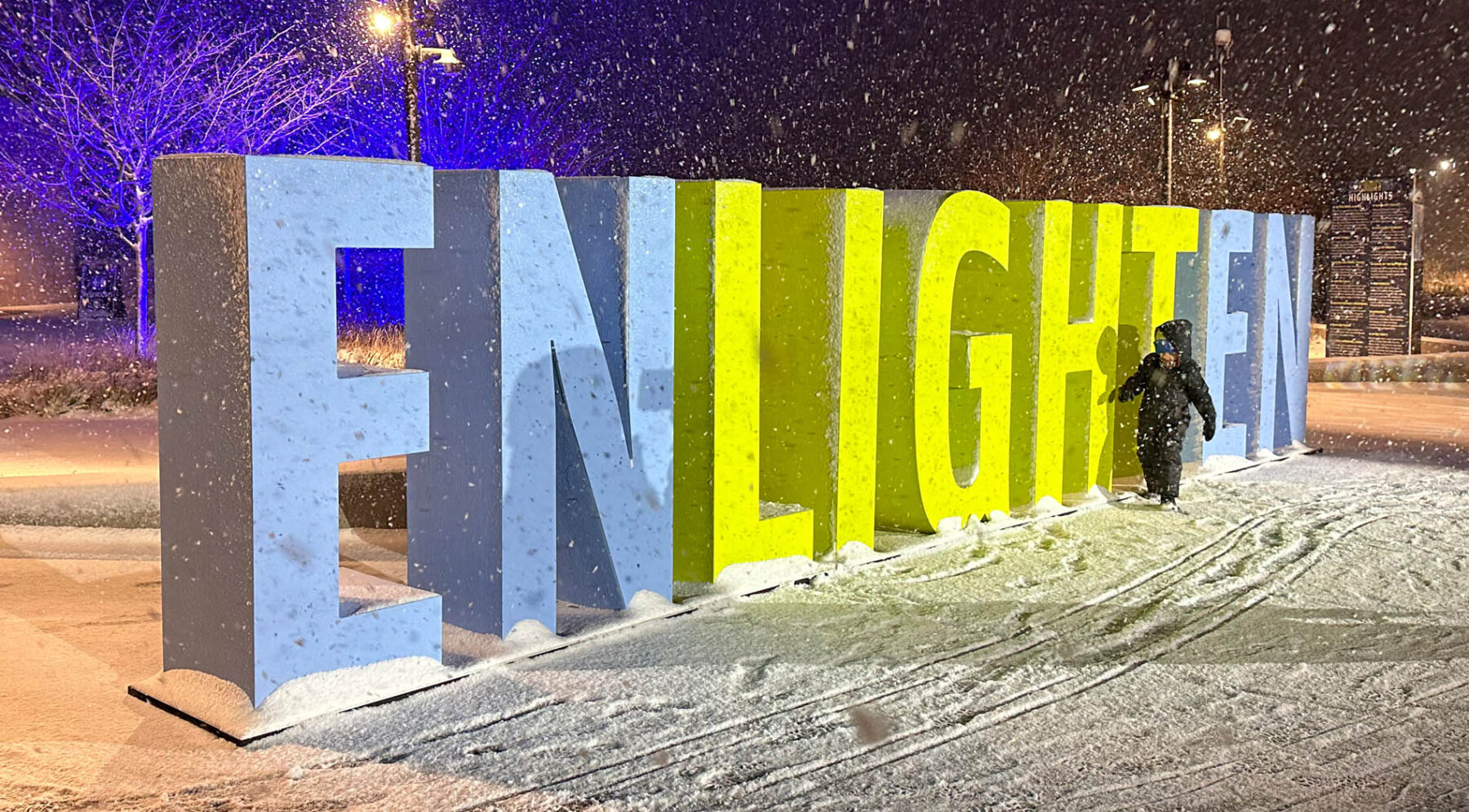 Installation featuring a block letter sculpture reading “Enlighten” for the Enlightened Exhibit