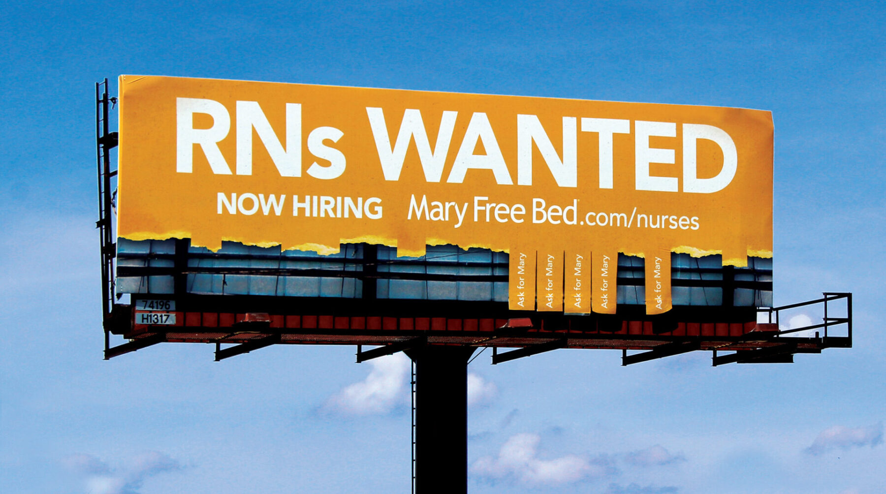 Billboard made to look like a take a number sheet with pieces ripped off the bottom, with the headline “RNs Wanted. Now Hiring.”