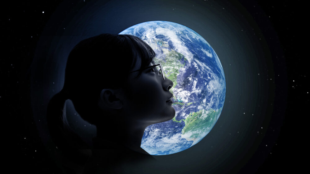Profile of woman's head in front of planet Earth.